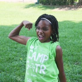 Girl with Camp GOTR shirt on showing her muscles.