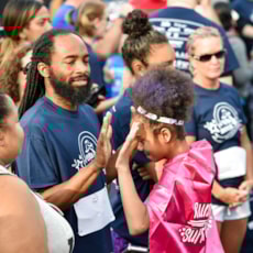 Girls on the Run participant high fives running buddy at 5K